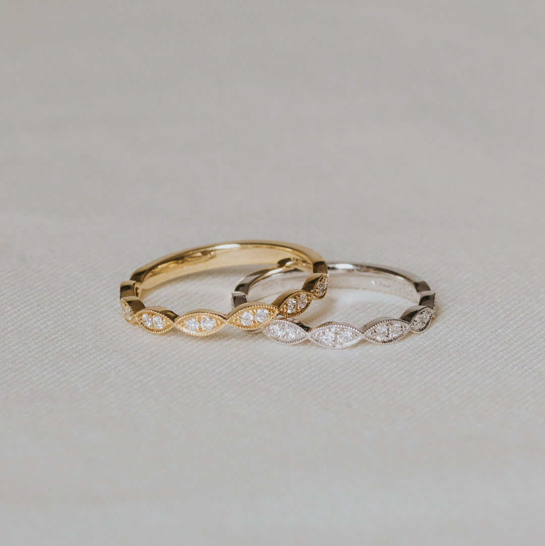 Two gold rings with diamond accents on a light gray background